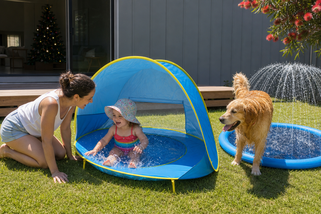 Summer Christmas in a New Zealand backyard: toddler splashing in the pop-up pool tent with mum beside her and the dog at the splash pad