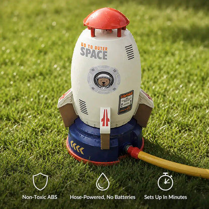 Rocket sprinkler on its launch base with a garden hose attached, showing non-toxic ABS, hose-powered and quick setup features