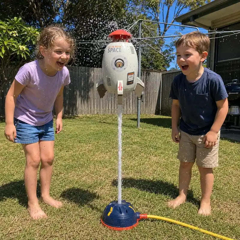 Two children watching a water-powered rocket sprinkler hover on a jet of water in an Australian backyard