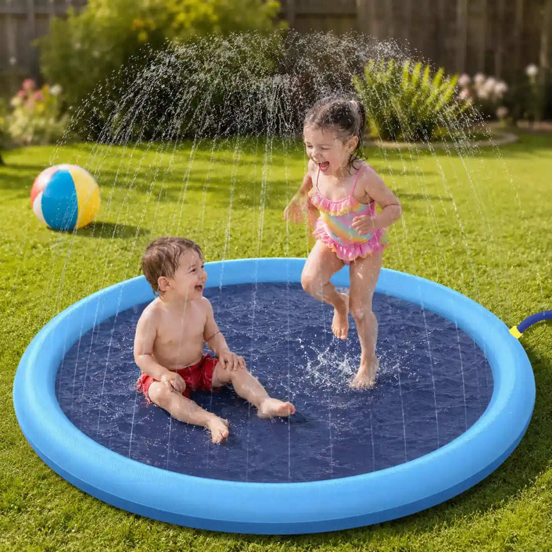 A toddler sitting and a young girl jumping through the water jets of a kids splash pad in a backyard
