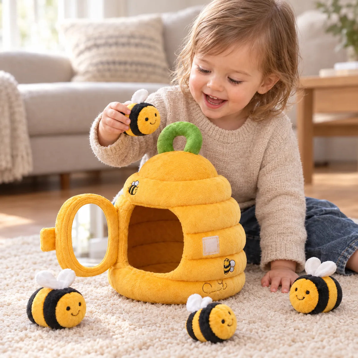 Toddler holding a plush bee above the open beehive with three more bees on the rug