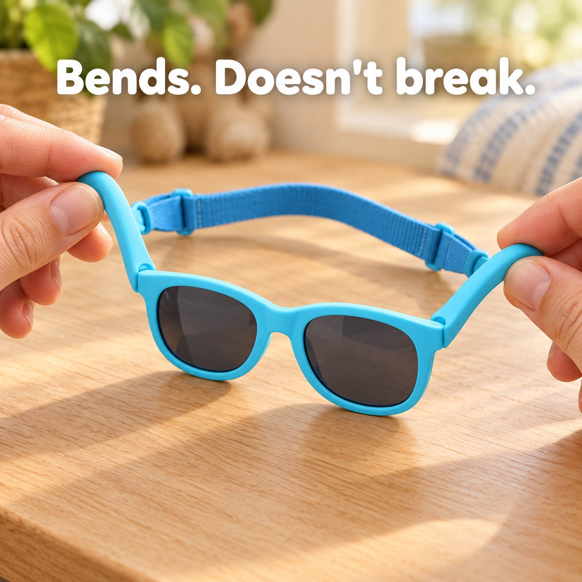 Hands bending the soft, flexible frame of blue baby sunglasses