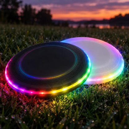Black and white light-up flying discs glowing on dewy grass at dusk