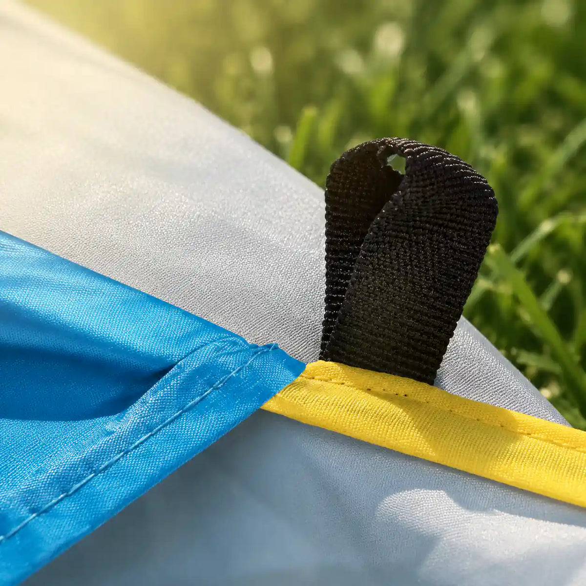 Close up of the reinforced webbing peg loop and yellow trim on the pop up beach tent