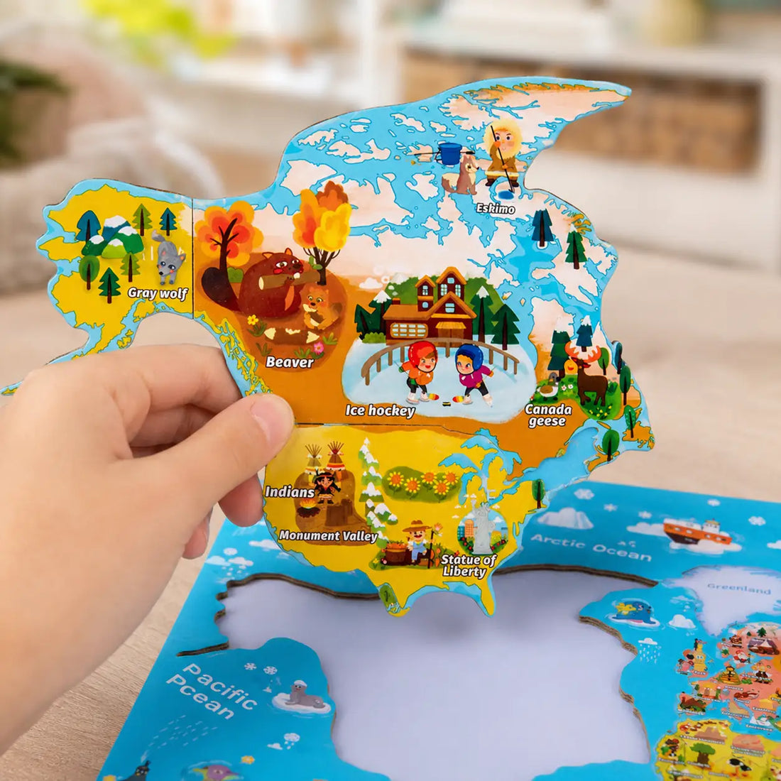 Child's hand lifting the magnetic North America piece clear of the world map board
