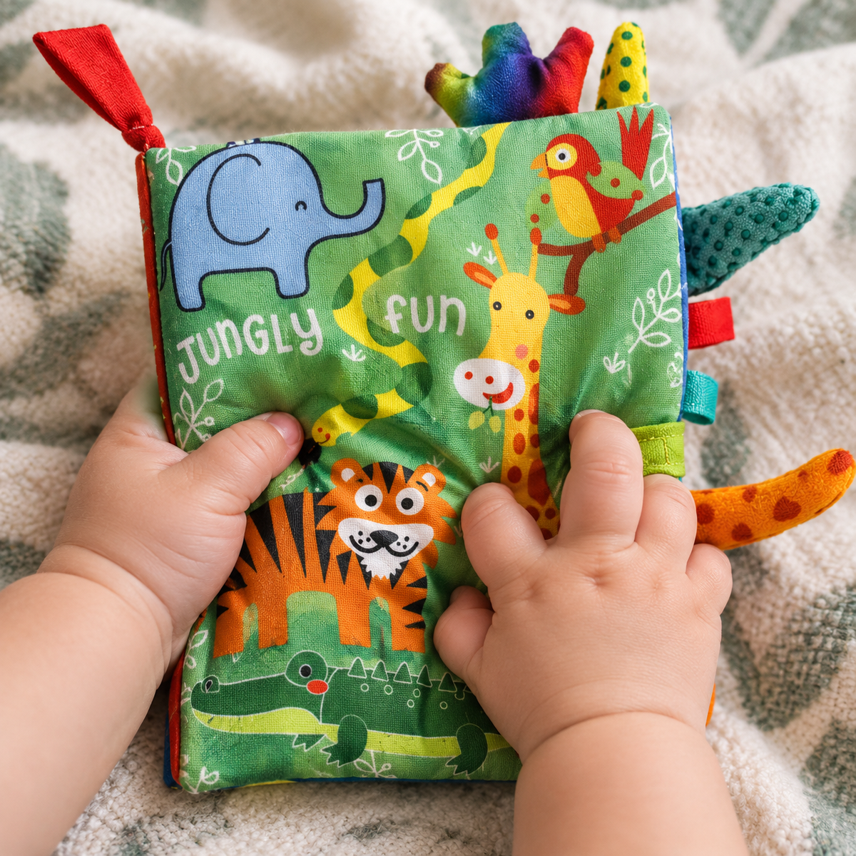 Baby's hands squeezing the crinkle cover of the soft jungle cloth book