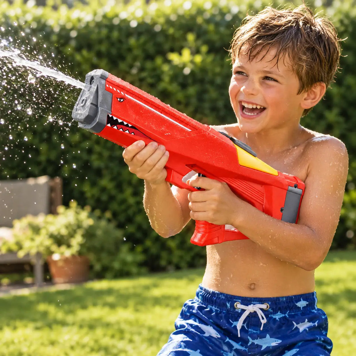Boy firing the red electric shark water blaster on a sunny lawn