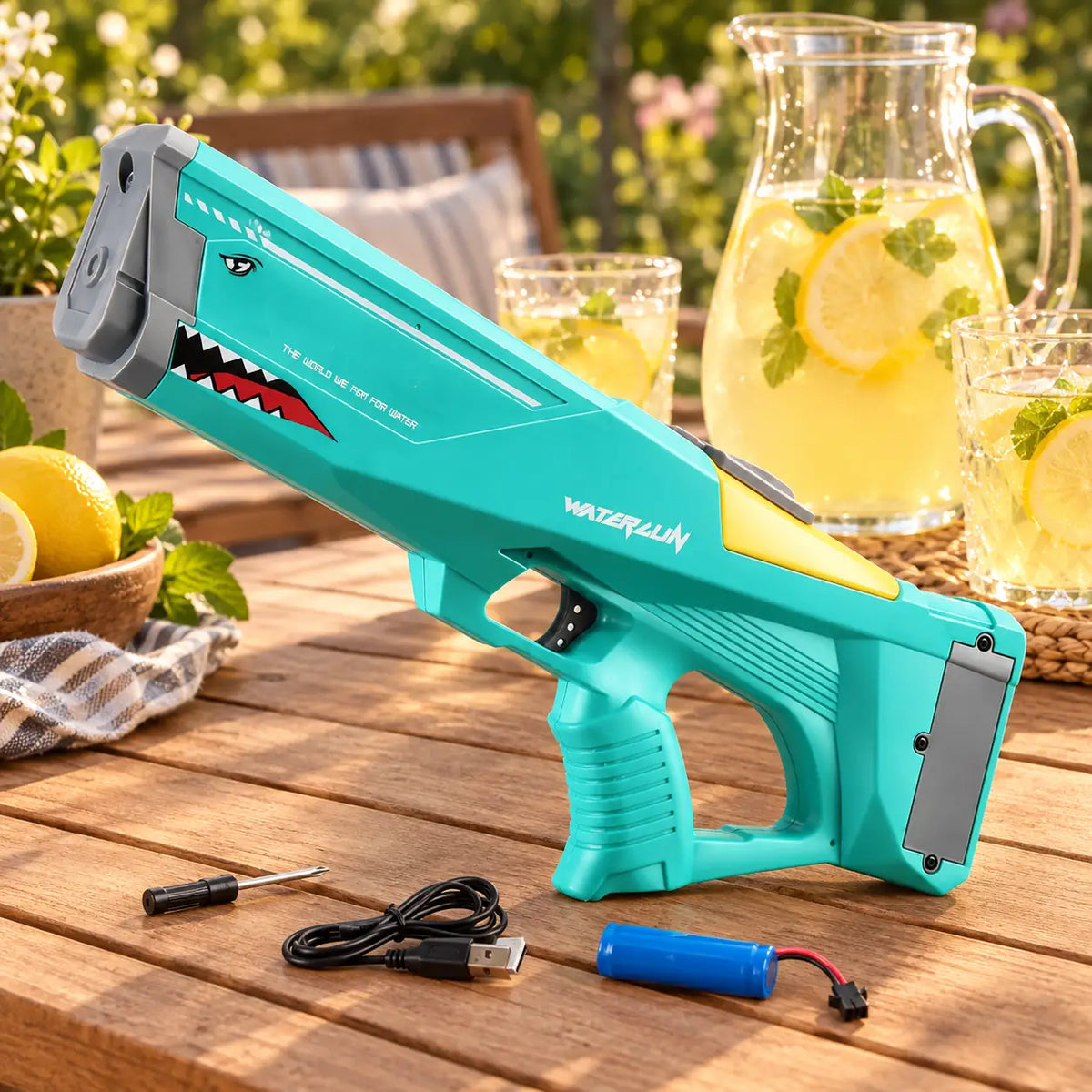 Green shark water blaster with its USB cable, battery and screwdriver on a garden table