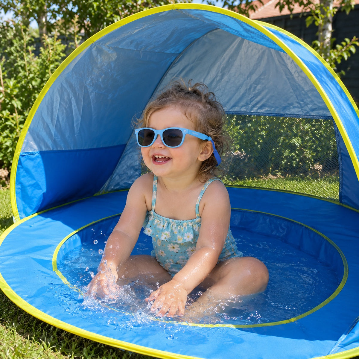 Toddler in blue sunglasses splashing in the Little Cubs pop-up pool tent