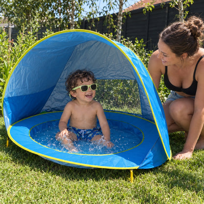 Toddler in light green sunglasses splashing in the Little Cubs pool tent