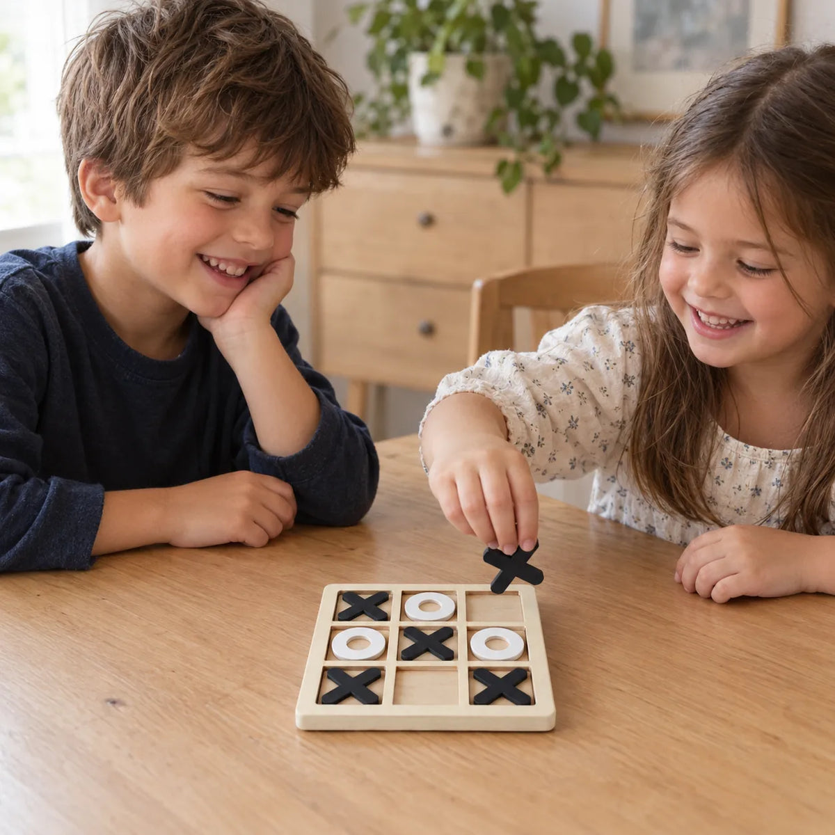 A brother and sister playing wooden tic tac toe across the kitchen table